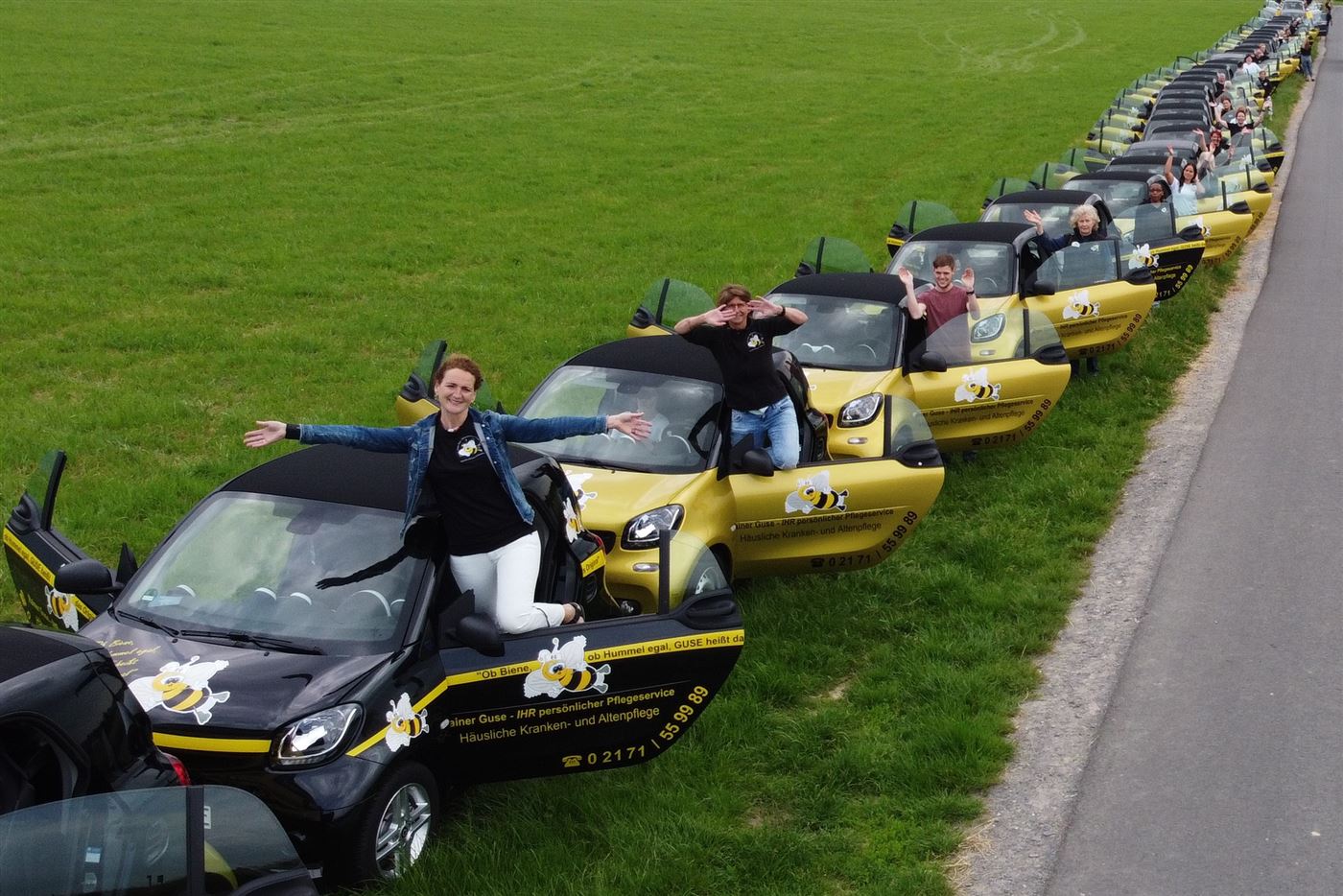 Team posiert auf den E-Dienstwagen