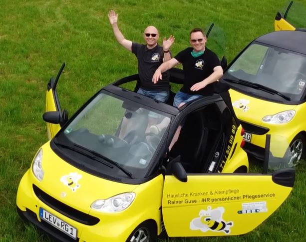 Zwei Kollegen jubeln aus einem Cabrio-Dienstwagen