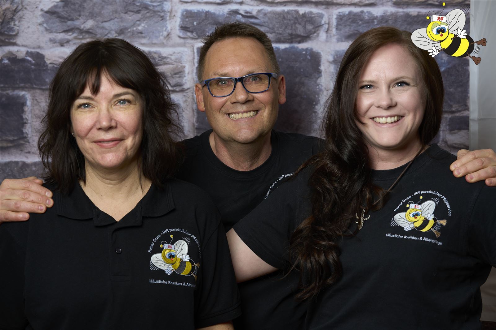 Lachende Mitarbeitende des Guse-Teams in schwarzen Shirts mit Bienen-Logo